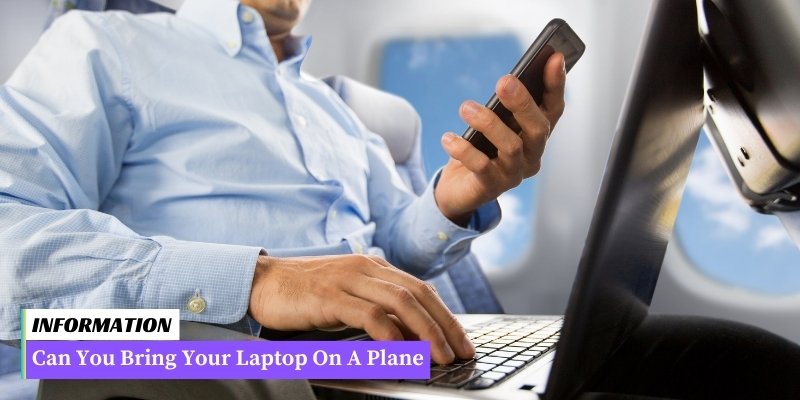 A person's hand holding a laptop while sitting on an airplane seat.